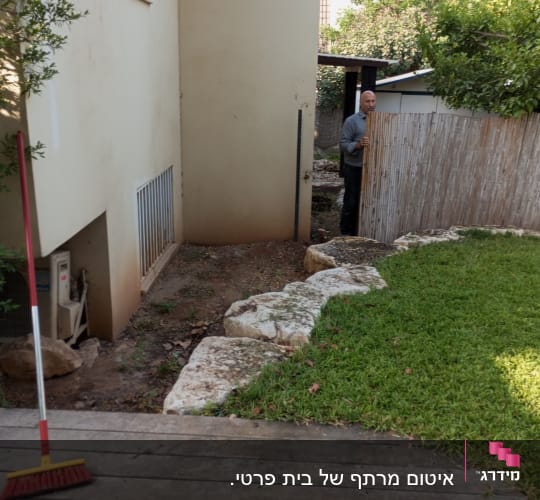 אדם עומד ליד גדר במרפסת עם מטאטא